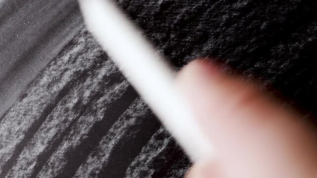close up of chalk pencil drawing on textured black paper. slow motion footage. Background video can be used as overlay. doodling hatching