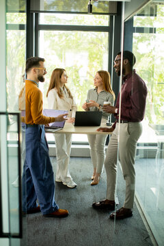 Group of four people having a conversation in a modern office during daylight hours
