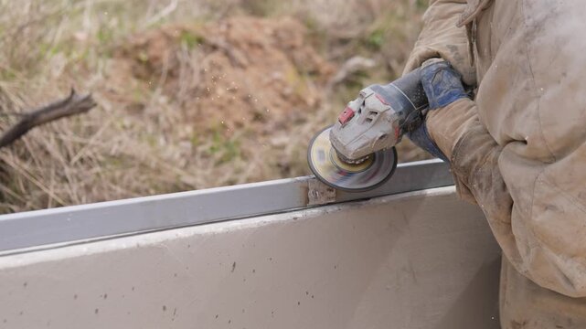Worker Grinding Metal Seam With Grinder, Angle Disc Smoothing Weld Bead And Creating Flying Sparks, Gloved Hands Steadying Frame, Outdoor Finishing And Surface Preparation For Installation
