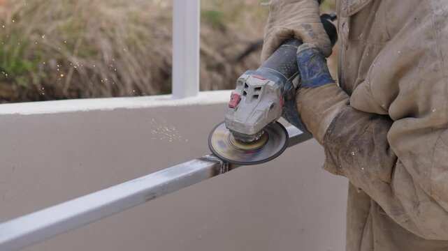 Contractor Performs Final Polish On Rail, Closeup Showing Abrasive Disc Removing Burrs And Creating Smooth Finish, Sparks Scattering, Steady Hands In Protective Gloves, Finishing Touch On New Fence