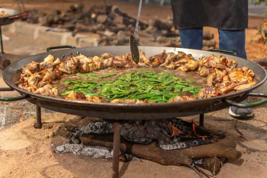 Traditional Valencian paella cooking outdoors over wood fire
