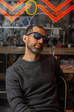 Young bearded man with sunglasses in neon lit restaurant