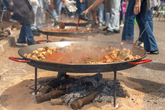 Traditional paella cooking over wood fire at outdoor gathering