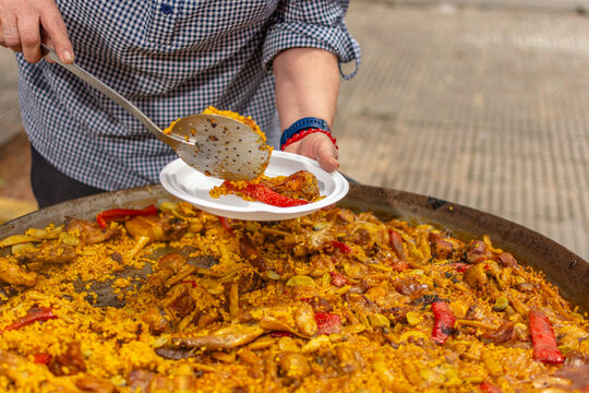 Senior woman serving traditional valencian paella on plate