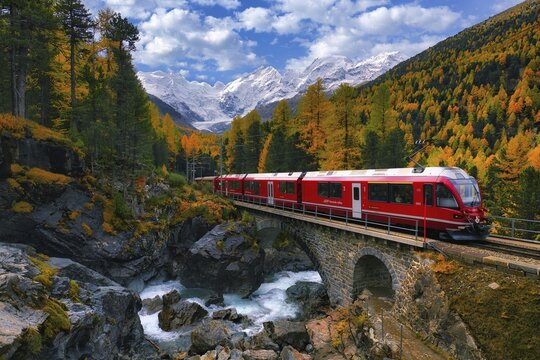 Rhaetian Railway RhB crossing a mountain stream over a stone bridge, behind it autumn-coloured Val Morteratsch with snow-covered mountains, Engadine, Canton Grisons, Switzerland