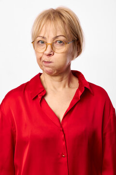 Senior woman portrait, short blonde hair, glasses, red shirt, facial expression, thoughtful awkward mood, isolated on white background