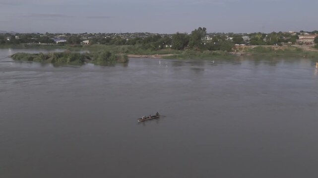 Drone does 360 around canoe in wide shot on Zambezi River with Samora Machel Bridge after sunset at twilight in Tete, Mozambique