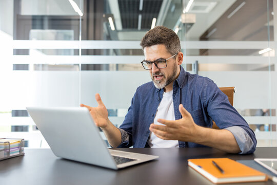 Frustrated entrepreneur or employee reacting with anger to a problem on his laptop, expressing stress and confusion over a technology failure during work in a modern office