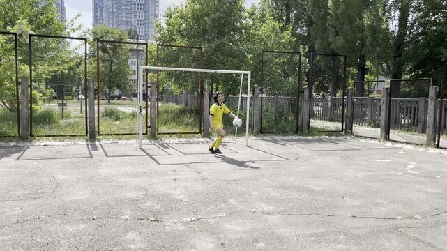 Teen soccer player dribbling ball and attacking goal on outdoor court youth football training action and offensive play concept. High quality FullHD footage