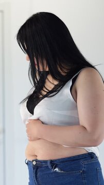 Curvy Caucasian Woman Checking Belly, Adjusting Jeans And White Top, Trying Fit, Measuring Waist, Examining Silhouette, Home Fitting Session, Intimate Self Care Moment, Contemplative Mood, Relatable
