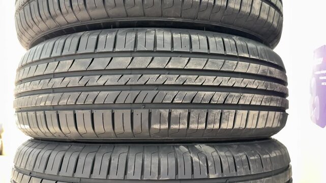 Stacked summer tires at pickup point, closeup of new tread patterns and rubber texture, retail inventory on pallets in outdoor