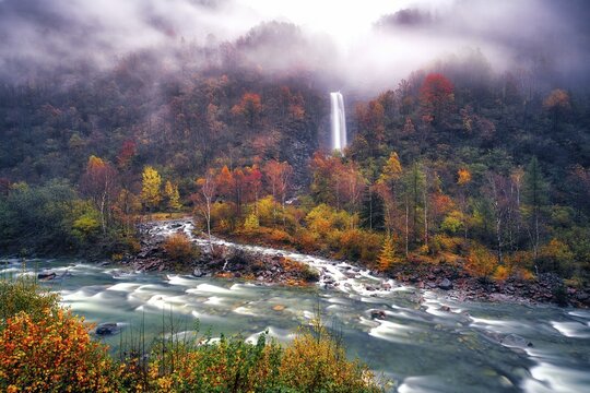 Waterfall with river Verzasca surrounded by autumn coloured deciduous trees, rainy and foggy Verzasca valley, Canton Ticino, Switzerland