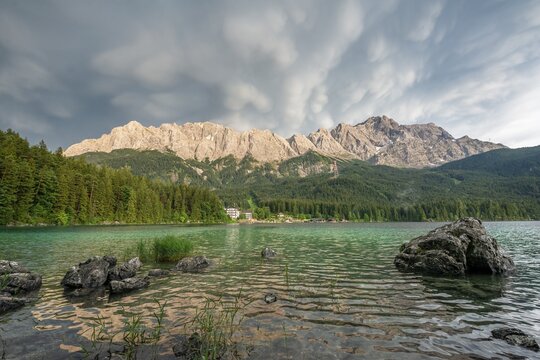 Rocks on the shore, Lake Eibsee lake in front of Zugspitze massif with Zugspitze, dramatic Mammaten clouds, Wetterstein range, near Grainau, Upper Bavaria, Bavaria, Germany