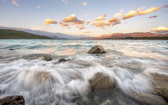 Stones on shore, lake with sunset swell, long time exposure, Lake Tekapo, Canterbury, South Island, New Zealand
