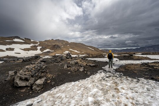 Hikers in snow-covered volcanic landscape with volcanic sand and petrified lava, crater of Askja volcano, Icelandic highlands, Iceland