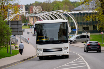 Naklejka premium Large tour coach navigating a metropolitan street with pedestrians and cars nearby, focusing on tourism industry travel and commuting solutions in a developed city