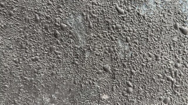 Close-up uniflex waterproofing membrane texture revealing gritty concrete surface with granular aggregate and small pebbles. Matte
