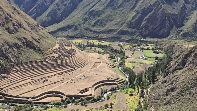 Llactapata, Peru - 23 June 2024. Close view of the terraced Llactapata Inca ruins on a mountainside above the Urubamba Valley, with stone terraces, paths, farmland, river, and Andes peaks.