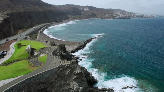 Beautiful aerial perspective of the Atlantic Ocean waves washing onto the dark volcanic sand of La Laja beach in Las Palmas, Gran Canaria