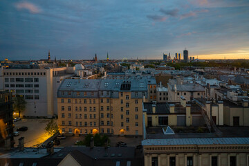 Evening cityscape of Riga's old and new districts showing rooftops and street lights illuminating courtyard areas under a cloudy sky for travel and real estate themes © K