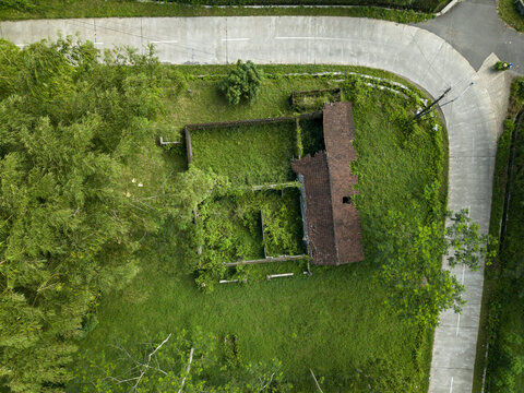 Aerial view of Houses Damaged by Mount Merapi Eruption with collapsed roofs and overgrown vegetation near a curved road in Cangkringan, Special Region of Yogyakarta, Indonesia.