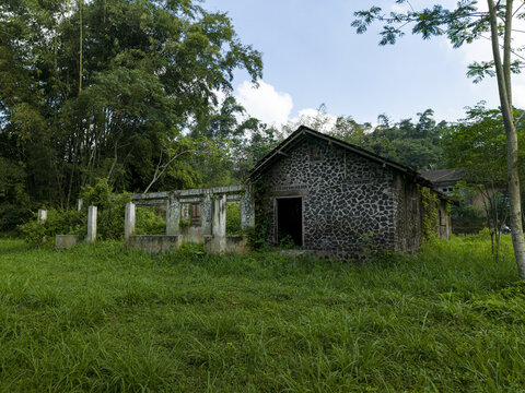 Aerial view of stone house ruins damaged by the Mount Merapi eruption surrounded by lush vegetation and trees in Cangkringan, Special Region of Yogyakarta, Indonesia.