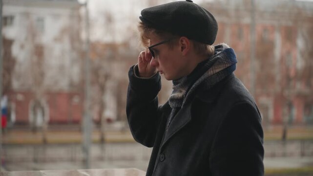 Artist views surroundings. Individual observes cityscape attentively. Person examines urban environment with reflective gaze. Creator carefully looks over city street through reflective glasses