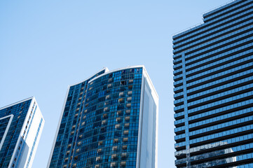 Obraz premium Modern high-rise residential buildings with glass facades against a clear blue sky.