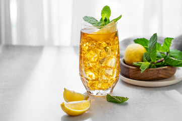 Fototapeta premium Iced tea with lemon and mint in a glass on a concrete countertop with citrus fruits