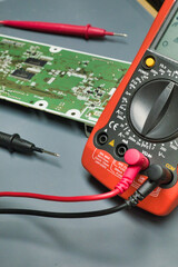 Fototapeta premium Orange digital multimeter with probes and pcb