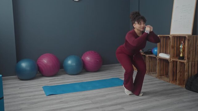 Woman performing lateral lunge with hands clasped over chest on yoga mat in studio; focus and strength.