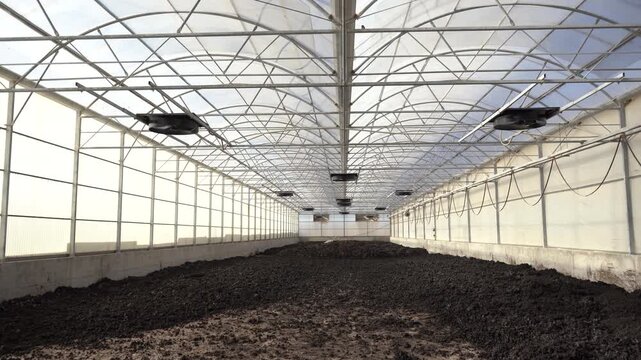 Cinematic pull-back shot of a solar sludge drying greenhouse at a wastewater treatment plant. Essential B-roll for projects on ESG, the circular economy, and sustainable industrial waste management.