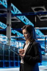 Fototapeta premium Data center software developer using tablet to inspect infrastructure rackmounts, updating network systems. IT expert using device to ensure stable server room operations, overseeing equipment rigs