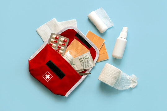 Top view of red first aid kit with band-aids, gauze,alcohol prep pap and pills
