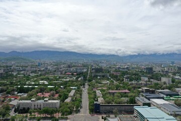 Obraz premium Aerial view of urban cityscape of Almaty with distant mountains under cloudy skies, Kazakhstan