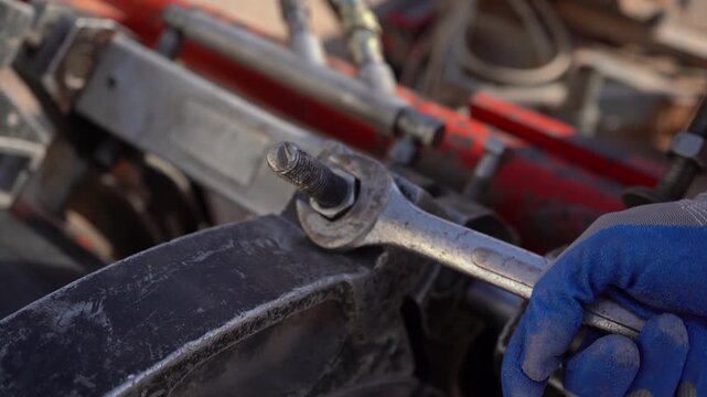 Close-up of a gloved worker using a wrench to tighten a nut on heavy industrial machinery. Essential B-roll for projects on mechanical repair, infrastructure maintenance, engineering, and manual labor