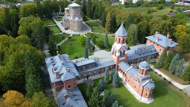 Drone aerial view of a beautiful Eastern Orthodox church surrounded by lush parkland, monastery buildings, and landscaped gardens. Scenic overhead perspective showcasing religious architecture, peacef