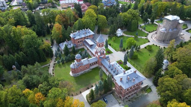 Drone aerial view of a beautiful Eastern Orthodox church surrounded by lush parkland, monastery buildings, and landscaped gardens. Scenic overhead perspective showcasing religious architecture, peacef