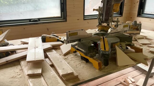 Power miter saw and wooden boards in workshop.
