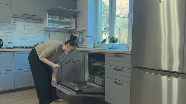 Dishwasher door being closed after loading dishes. Common kitchen cleaning routine and appliance usage
