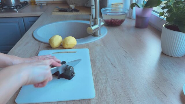 Knife sharpening process using sharpener tool preparing kitchen knife for cutting. 