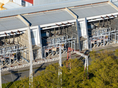 Aerial view of an electrical substation featuring high-voltage transformers, power lines, and industrial infrastructure surrounded by green trees Slovenia.
