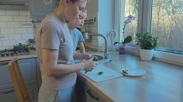 Sliced feijoa placed into plate while child watches nearby. Family cooking moment and healthy eating routine.