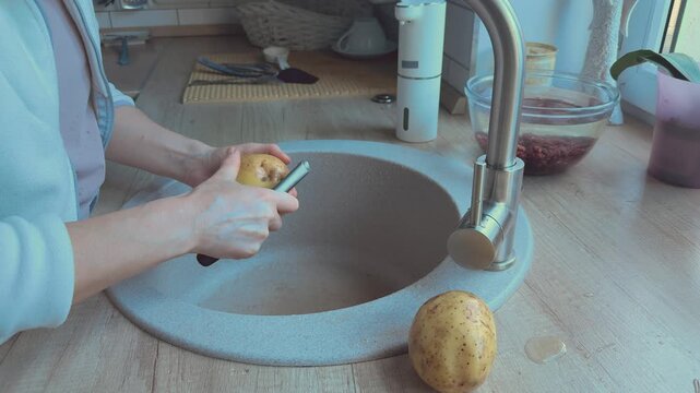 Thin potato skin peeled carefully preparing vegetables for homemade food. 