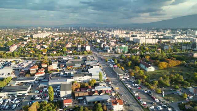 Drone aerial panorama of a densely populated residential district in Sofia, Bulgaria featuring apartment buildings, city streets, parks, and the skyline with Vitosha Mountain in the background. Wide e