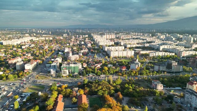 Drone aerial panorama of a densely populated residential district in Sofia, Bulgaria featuring apartment buildings, city streets, parks, and the skyline with Vitosha Mountain in the background. Wide e