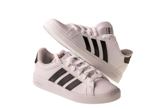 Close up of white adidas sneakers isolated on white background with black stripes and casual style. Sweden. 