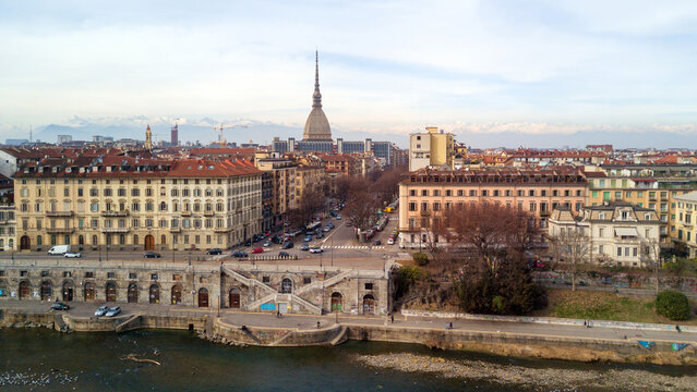Aerial view of the Mole Antonelliana rising above the city skyline with the Po River in the foreground and snow-capped Alps in the distance Turin, Piedmont, Italy.