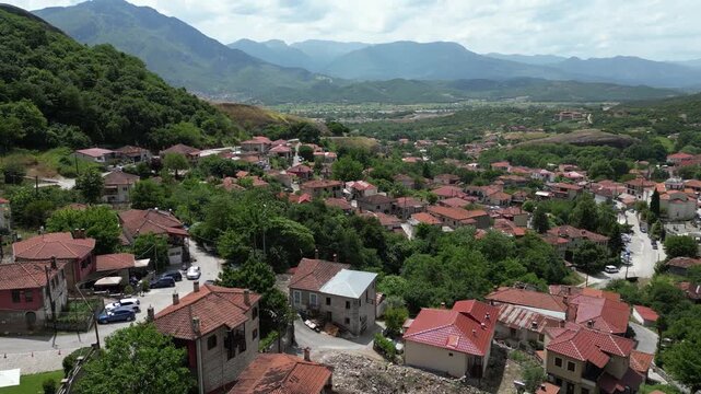 Aerial View of Greek Village. Kastraki in Meteora. Red Terracotta Roof Tiles Slow Drone Backwards Blue Sky with Clouds. European Town