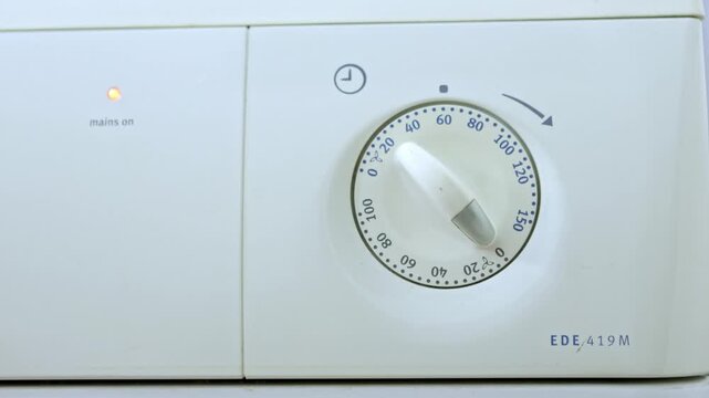 Person setting the timer on a washing machine dial